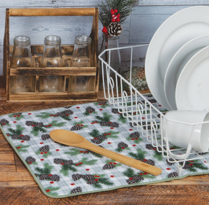 Dish drying rack with plates, wooden spoon, and decorative mat on a wooden surface.