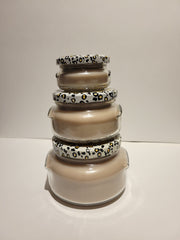 Stack of three round candles with animal print lids, in shades of beige and brown, from Tyler Candle Company.