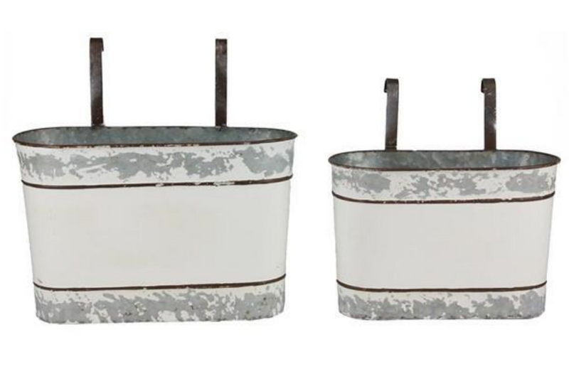 Two metal planters with distressed white finish and black handles on a white background