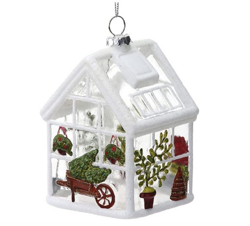 Decorative glass greenhouse ornament with plants and a wheelbarrow on a white background