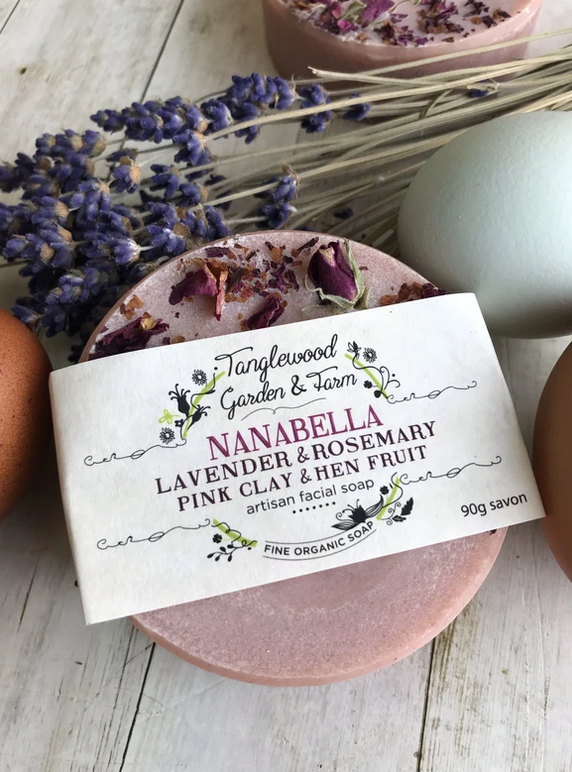 Bar of soap with a label on a wooden surface with lavender and rosemary.