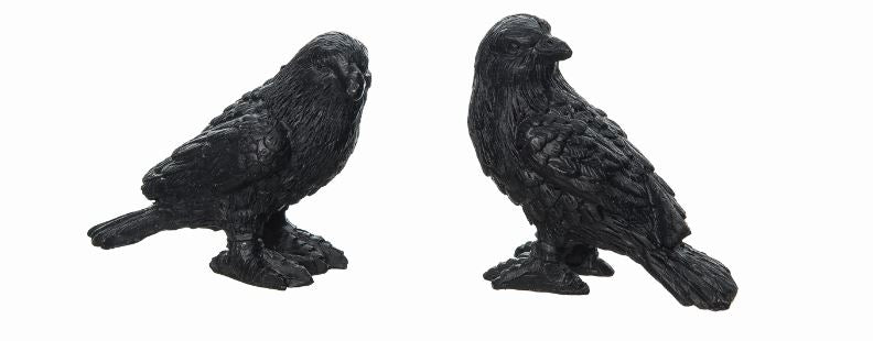 Two black crow figurines on a white background