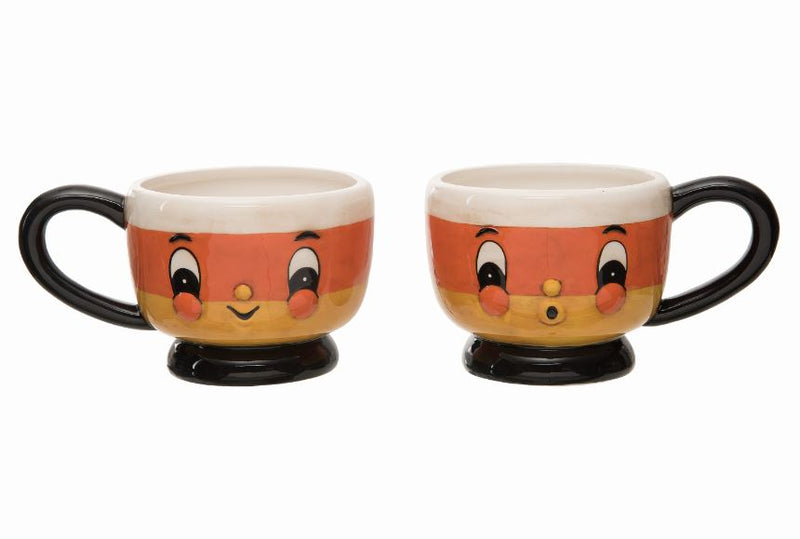 Two candy corn-themed mugs with face designs on a white background